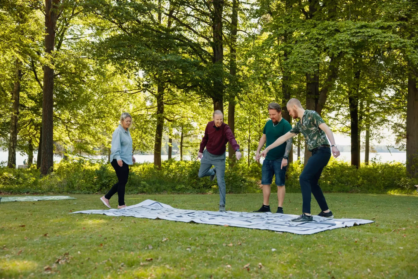 Tre personer står på en lekmatta utomhus på gräs.