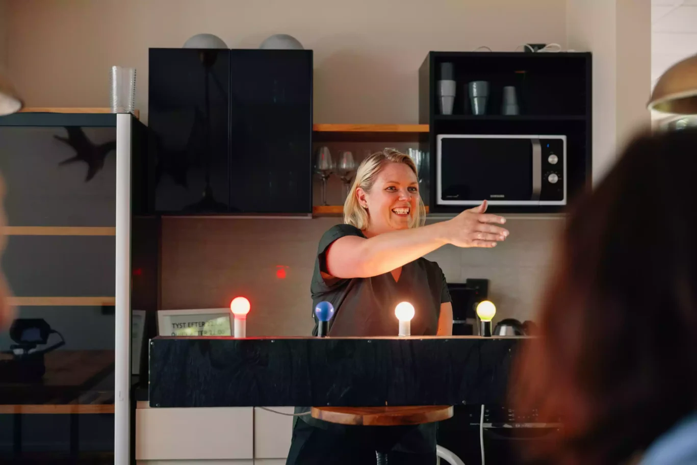 Kvinna står bakom färgade glödlampor som lyser under en lek