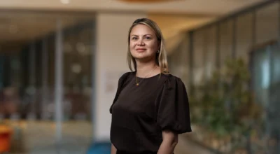 Kvinna med brun blus tittar in i kameran och ler